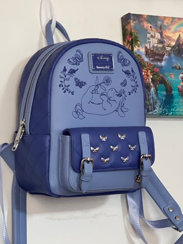 Customer's blue Loungefly Eeyore backpack hanging on a wall, showing the embroidered graphic and quilted front pocket.