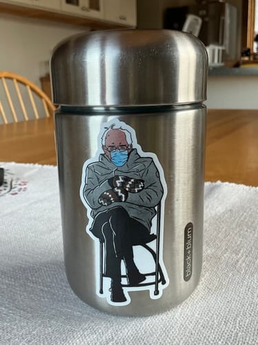 Customer's Bernie Sanders Chair Sticker applied to a brushed stainless steel thermos sitting on a table.