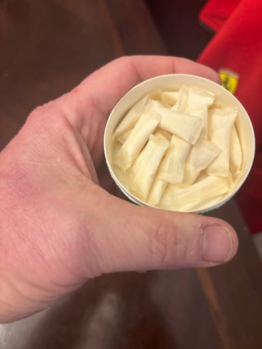 A reviewer's hand holds an open can of Tropical Fruit Nicotine Pouches, showing the moist pouches inside.