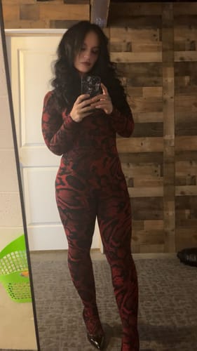 Reviewer takes a full-length mirror selfie wearing the red and black animal print Naked Print Jumpsuit.
