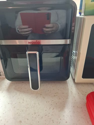 Client arătând friteuza sa neagră Air Fryer Novio StonePro pe un blat de bucătărie.