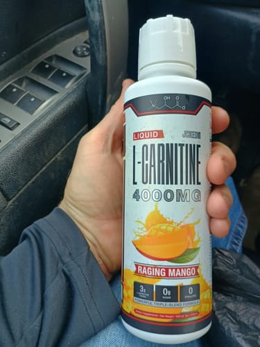Customer holds their bottle of Liquid L-Carnitine 4000MG in Raging Mango flavor while in a car.