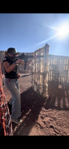 Reviewer wearing GS Extreme 3.0 hearing protection while aiming a rifle at an outdoor shooting range.