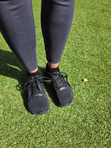 Reviewer wearing the all-black MUUV Flow pickleball shoes while standing on green grass.