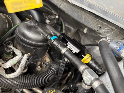 Reviewer's black SPE Motorsport Injector Return Repair Kit installed in the engine bay of a Powerstroke truck.