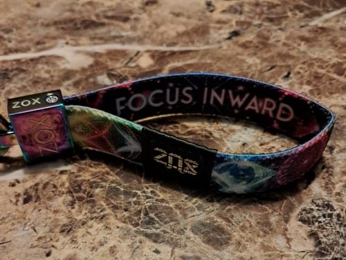 Customer's colorful Focus Inward Bracelet with its iridescent clasp resting on a marbled surface.