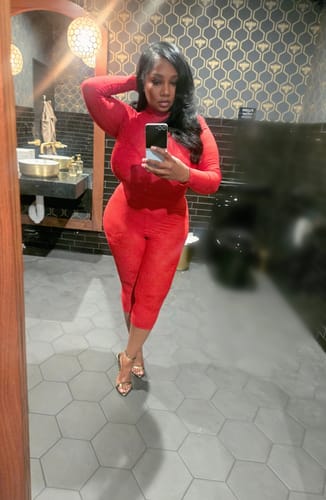 Reviewer taking a mirror selfie in a red Stretch Lace Sculpt Bodysuit and matching leggings.