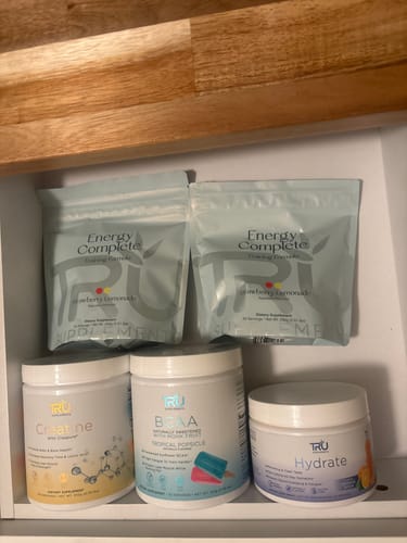 Reviewer's collection of TRU supplements in a drawer, featuring two light blue pouches of Energy Complete.