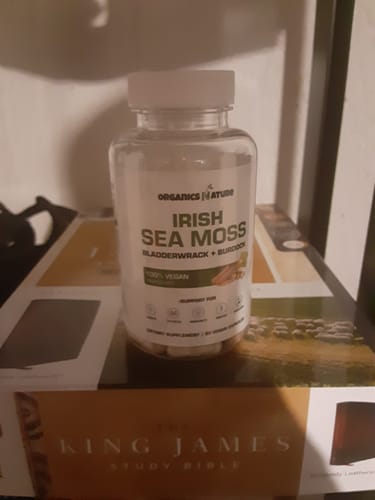 Customer's bottle of Organic Irish Sea Moss capsules with Bladderwrack and Burdock Root, placed on a book.