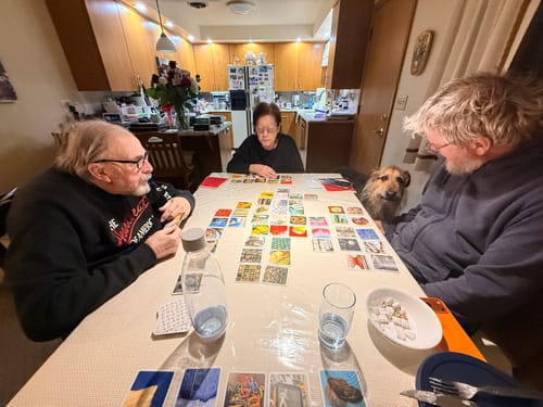 Customer's family gathered at a table, engaged in a game with OuiSi Original photo cards spread out before them.