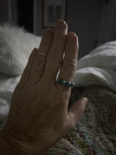 A customer's hand wearing the Turquoise Band Ring with its row of stones.
