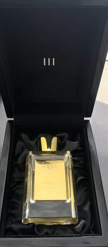 Reviewer's White Oud perfume bottle with a gold cap, presented in its elegant black box.
