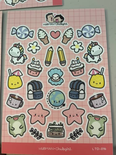 Reviewer holding a sticker sheet with cute unicorns, cupcakes, pencils, and backpacks for the STICKERS Promoproduct.