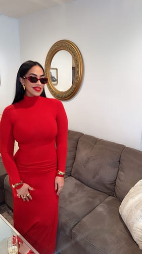 Reviewer standing indoors showing the full-length, fitted style of the red Butter Turtleneck Maxi Dress.