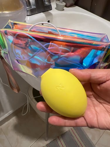 Reviewer holding the yellow Lem Clitoral Massager in their hand in a bathroom.