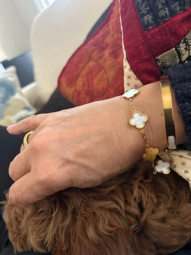 Customer wearing the White Clover Bracelet on their wrist, layered with another gold bangle.