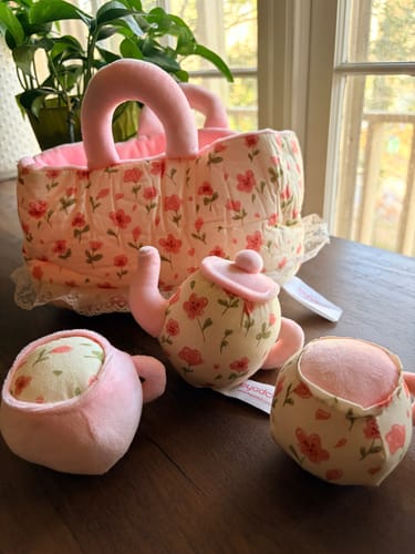 Customer's A Little Teapot Playset on a wooden table, showing the plush floral basket, teapot, and two teacups.