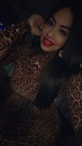 Close-up of a reviewer smiling while wearing the Naked Leopard Maxi Dress in a car at night, showing the mock neckline.