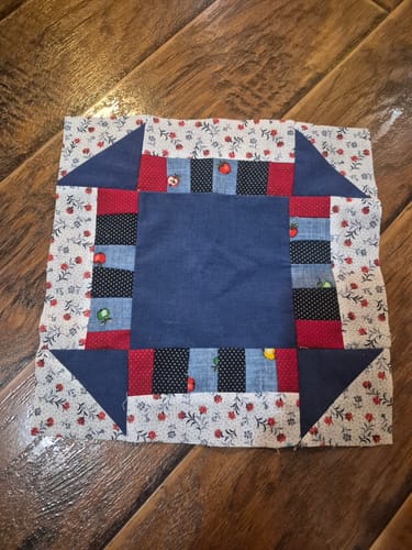 Reviewer's first completed quilt block from the Mrs Quilty subscription box, showing colorful patterned fabrics.