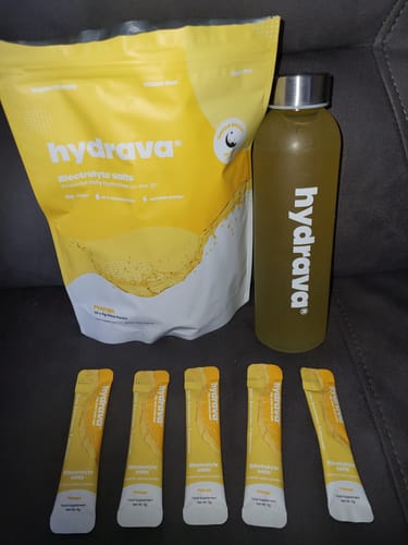 Customer's mango-flavored Hydrava electrolyte salts pouch, stick packs, and mixed drink in a branded water bottle.