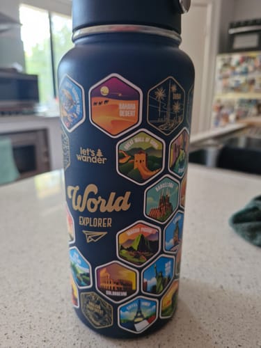 Customer's dark blue World Explorer Bottle covered with colorful, hexagonal landmark stickers.