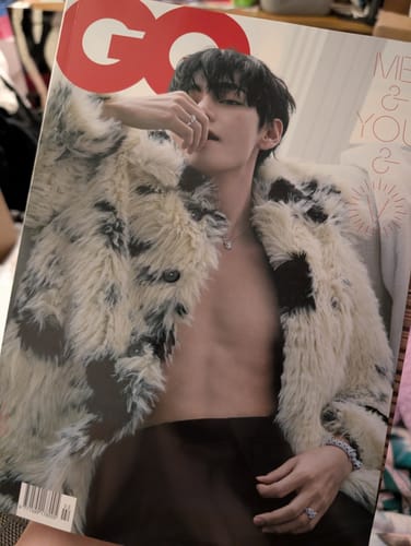 Reviewer holding their GQ Magazine, featuring BTS V on the cover in a fluffy, spotted coat.