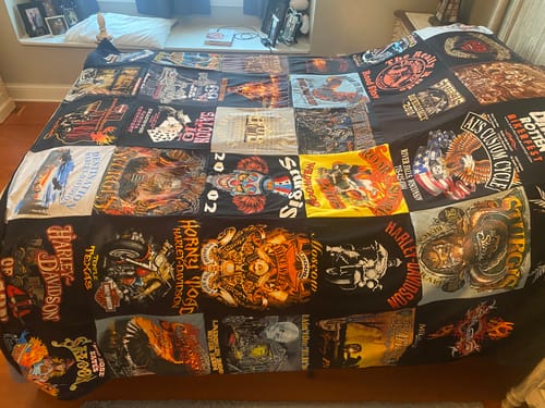 Customer's large Premium T Shirt Quilt with a black backing, made from various motorcycle-themed t-shirts and spread on a bed.
