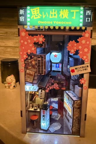 Customer's assembled Omoide Yokocho Book Nook Kit lit up, showing a detailed miniature Japanese alley scene.