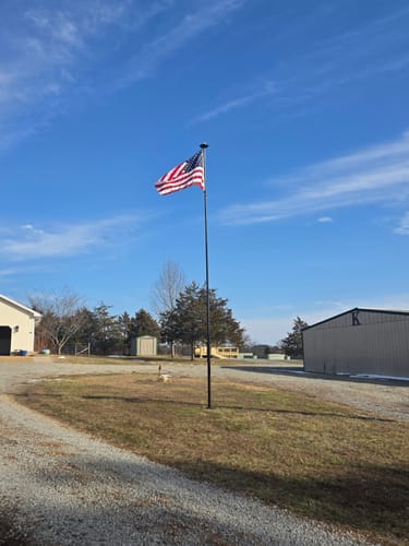 Customer's Heavy Duty American Nylon Flag waving on a tall flagpole in a yard against a blue sky.