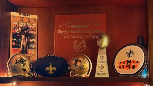 Customer's New Orleans Saints Super Bowl XLIV art displayed on a shelf with other Saints memorabilia.