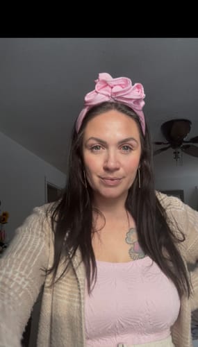 Reviewer wearing the pink ruffled Crawford Moire Headband in their hair.