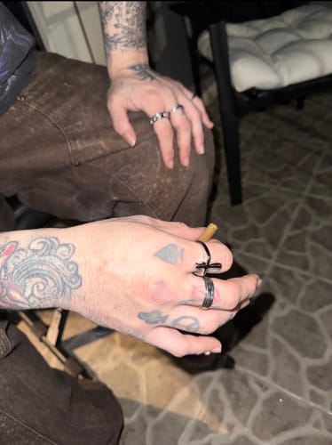 Customer's tattooed hand wearing the silver Psychedelic Love Ring and other rings.
