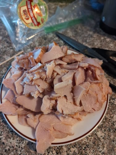 Customer's Halal Smoked Chicken Breast, sliced and piled on a white plate with the packaging in the background.