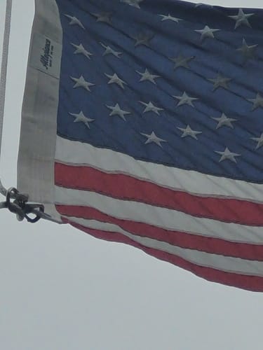 Close-up of a reviewer's stainless steel Flag Snap Hook securing an American flag to a thick rope.