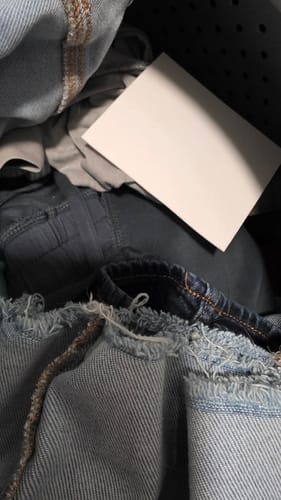 Customer's single Laundry Detergent Sheet on a pile of denim clothes inside a washing machine.
