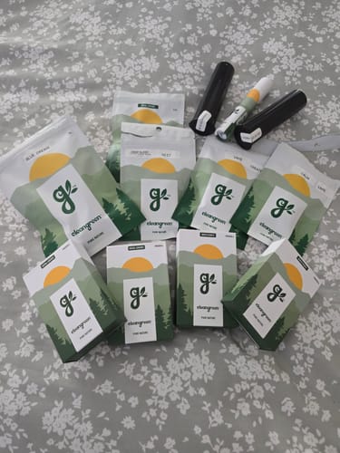 Customer's collection of various cannabis products, including Cherry Dosi Do Pre-Rolls, spread out on a floral blanket.