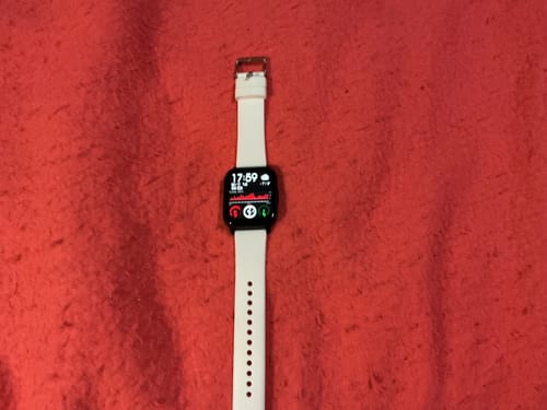 Customer's Gard Pro Health Smartwatch 2 with a white band, laid on a red surface with the screen activated showing health metrics.