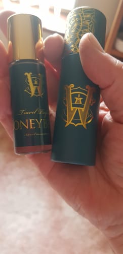 Customer holding the travel-size Honeyberry perfume bottle and its matching dark green carrying case.