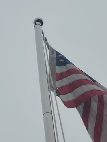 Customer's stainless steel Flag Snap Hooks attaching an American flag to a silver flagpole.