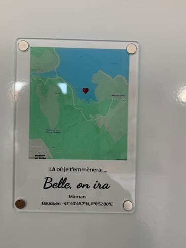 Rezensent zeigt den personalisierten „Notre événement“-Magneten mit einer Karte, einem Herz und Text.