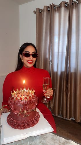 Customer wearing a red Butter Turtleneck Maxi Dress while sitting at a table with a birthday cake.