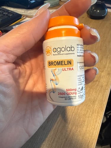 Recensore tiene in mano il flacone bianco di Bromelin Ultra con tappo arancione.