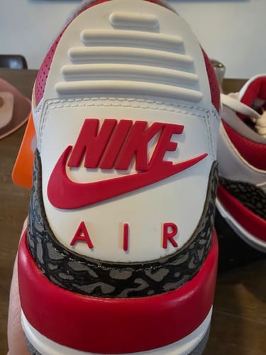 Close-up: de hiel van de Air Jordan 3 OG Fire Red van een recensent, met het rode 'NIKE AIR'-logo.