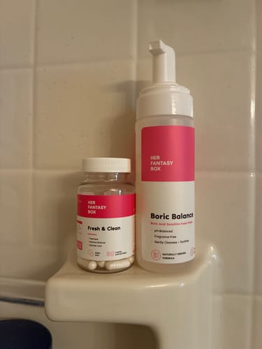 Customer's Fresh & Clean Kit duo, featuring the boric acid wash and suppository capsules, resting on a tiled shower shelf.