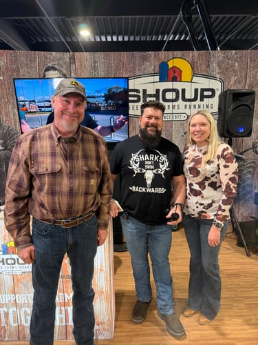 Reviewer wearing the cow print long sleeve mesh top while standing with two men at an indoor event.