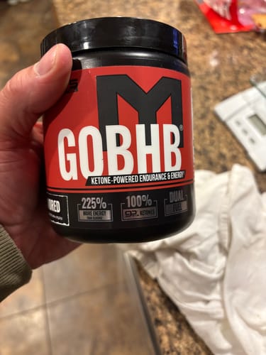 Customer holding the black and red tub of MTS Nutrition goBHB supplement.
