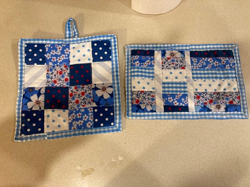 Customer's finished quilting projects from a Mrs Quilty Subscription Box, showing a blue and white patchwork potholder and mat.