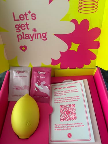 Customer's new yellow Lem Clitoral Massager shown inside its colorful packaging with included accessories.
