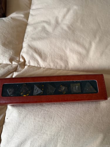 Customer's brown URWizards Leather Dice Display Box holding a set of dark dice on a bed.