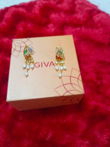Reviewer's Golden Parvati Earrings with colored stones and pearl drops, resting on the branded GIVA box on a red surface.